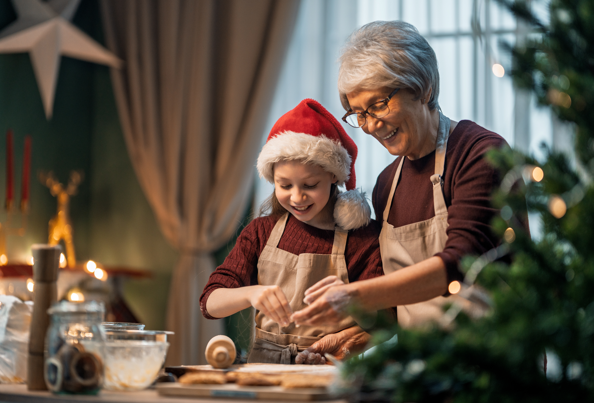 A senior woman makes Christmas cookies with her granddaughter